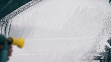 Oto yıkama deterjanı araba yıkarken veya araba yıkarken lüks bir arabadan damlıyor.