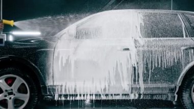 Oto yıkama deterjanı araba yıkarken veya araba yıkarken lüks bir arabadan damlıyor.