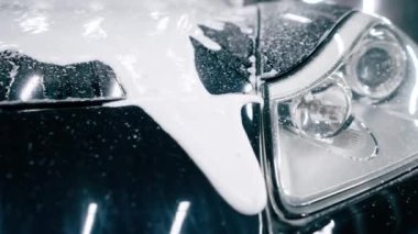 Otoparkta ya da araba servisinde temizlik yaptıktan sonra ön far tamponunda araba yıkama ve siyah lüks bir arabanın ızgarası.