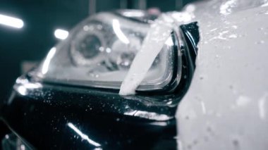 Otoparkta ya da araba servisinde temizlik yaptıktan sonra ön far tamponunda araba yıkama ve siyah lüks bir arabanın ızgarası.