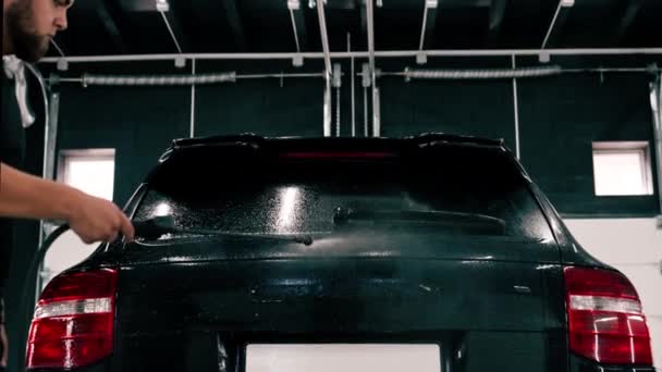 黒い高級車は自動車化学薬品で洗浄し 洗浄する間洗車の箱に立っています — ストック動画