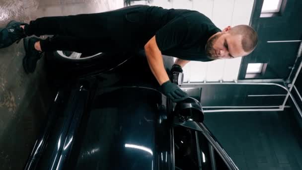 黒い手袋に焦点を当てた男性用洗車労働者は スポンジカーケアのコンセプトを垂直に磨くことによって高級ブルーカーの鏡を磨きます — ストック動画