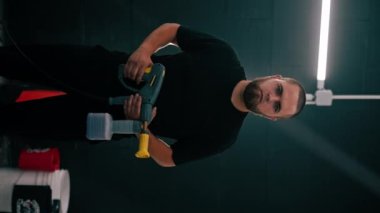 Araba yıkama işçisinin sakallı, elinde köpük jeneratörü olan ciddi bir adamın portresi. Araba bakım konseptini dikey tutuyor.