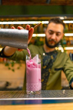 Deneyimli barmen taze alkollü kokteylleri Shaker 'dan cam bar restoranına döker.