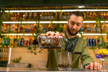 Deneyimli barmen kadehten cam bar restoranına taze alkollü kokteyl döker.