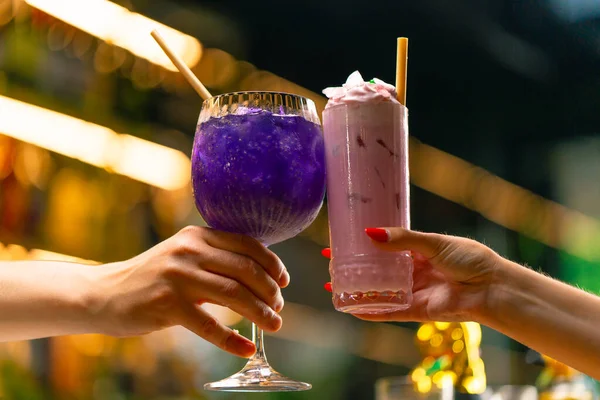 Close up of two people cheering cocktails in a bar disco club drinks and cocktails concept