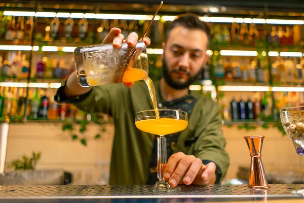 Deneyimli barmen kadehten cam bar restoranına taze alkollü kokteyl döker.