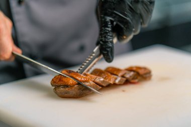 Profesyonel restoran aşçısı Asya mutfağına yakın bıçaklı lezzetli kızarmış ördek göğsü kesiyor.