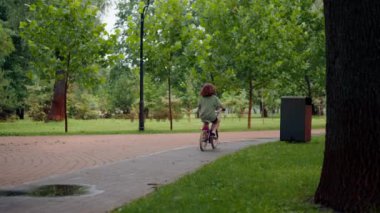 Arkaya bakan anne mutlu çünkü kızı parkta ilk kez tek başına bisiklete biniyor. Mutlu bir çocukluk.