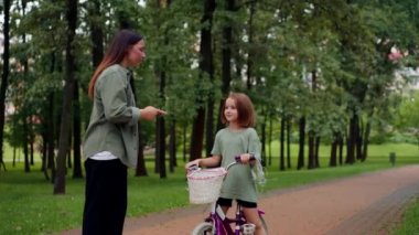 Genç anne, hızlı bisiklet süren yaramaz çocuk ağladığı için parkta kızını azarlıyor.
