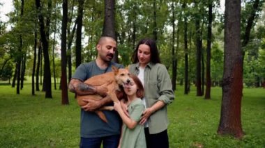 Parktaki mutlu genç ailenin portresi köpek babasıyla anne kızının dinlenme konsepti güven bakımı ve aile değerleri.