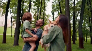 Parkta mutlu genç bir aile köpek babası kızını kucağında tutuyor güven bakımı ve aile değerleri