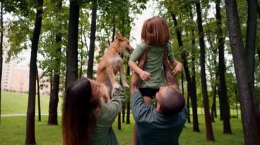 Parkta mutlu genç bir aile köpek babası kızını kucağında tutuyor güven bakımı ve aile değerleri