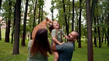 Parkta mutlu genç bir aile köpek babası kızını kucağında tutuyor güven bakımı ve aile değerleri