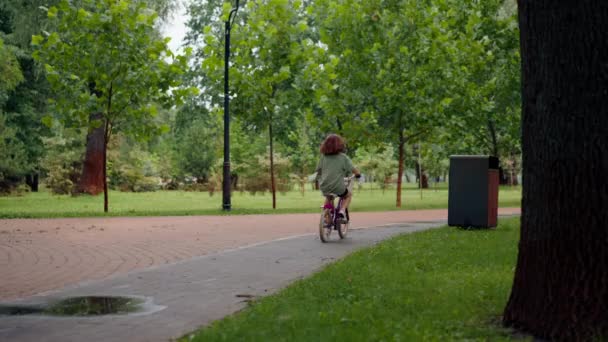 バックビューのお母さんは 娘が公園で初めて一人で自転車に乗っているので幸せです — ストック動画