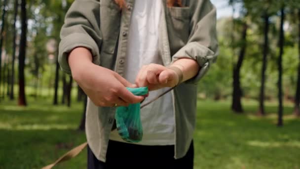 閉じる 都市公園の芝生から犬のポップを拾う女性 女性はペット排泄物の環境保護と青いビニール袋を保持しています — ストック動画