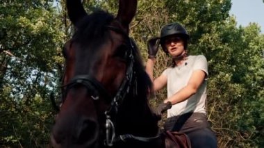 Profesyonel ekipman giymiş bir sürücü yürüyüş sırasında ormanda güzel atına biner. Hayvanlara olan aşkı sırasında.