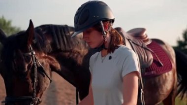 Profesyonel üniformalı bir kadın binici, at binme etkinliği sırasında açık havada koşum takımı ile güzel siyah atını sürüyor.