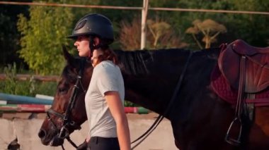 Profesyonel üniformalı bir kadın binici, at binme etkinliği sırasında açık havada koşum takımı ile güzel siyah atını sürüyor.