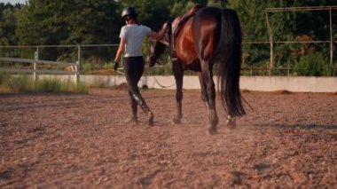 Profesyonel üniformalı bir kadın binici, at binme etkinliği sırasında açık havada koşum takımı ile güzel siyah atını sürüyor.
