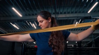 Güçlü kolları olan sportif kız sıkı bir idmana hazırlanıyor. Parmaklarını jimnastik salonunda korumak için yumruklarına bandaj yapıştırıyor.