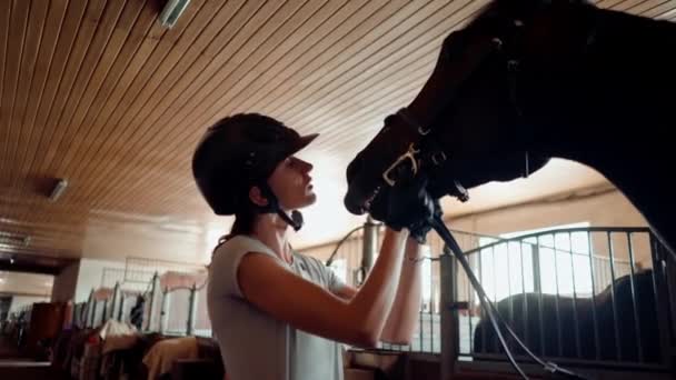 骑手头戴安全帽 在骑马前亲吻马厩里的马 — 图库视频影像