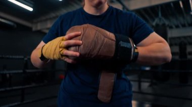Kız boksör, ringde spor eğitimine başlamadan önce bandajların üzerine kahverengi boks eldiveni giyer.