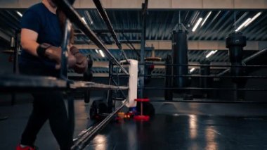 Eldivenli boksör kız halatlara tırmanıyor dövüşmeden önce spor salonunda boks ringine giriyor.