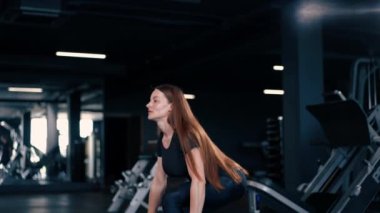 Vücut geliştirme müsabakasında ellerindeki dambıllarla egzersiz yapan konsantre fitness kadın antrenörü.