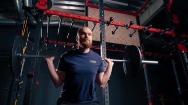 Genç motivasyonlu vücut geliştirici ağır halter spor salonunda aktif vücut bakımı yapıyor.