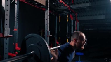 Genç motivasyonlu vücut geliştirici ağır halter spor salonunda aktif vücut bakımı yapıyor.