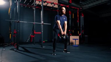 Spor salonunda grup çalışması yapan bir sporcu. Kettlebell egzersizleri yapar, yarışmaya hazırlanır.