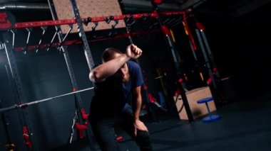 Eğitimden sonra spor salonunda yorgun bir sporcunun portresi alnından terini eliyle siler.