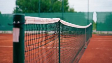 Açık hava tenis kortlarında spor ekipmanlarını eğiten bir ağ.