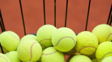 Tenis antrenmanı ya da tenis kortu müsabakasına başlamak için sepetten tenis topu alan bir elin yakın çekimi