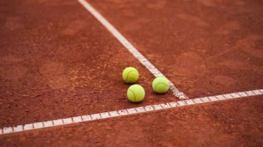 Küçük parlak toplar dışarıda oynayan kil tenis kortunda profesyonel spor eğitimi hobisi yatıyor.