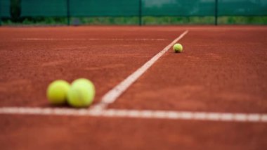 Küçük parlak toplar dışarıda oynayan kil tenis kortunda profesyonel spor eğitimi hobisi yatıyor.