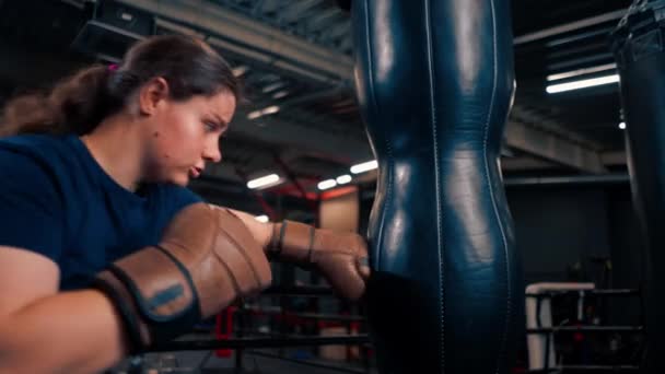 一个戴手套的女拳击手在拳击袋上打拳的力量在比赛前训练得很吃力 — 图库视频影像