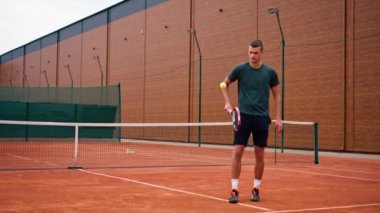 Genç tenisçi koç tenis kortunda raketle topa vuruyor ve spor yaşam tarzı yarışmasına hazırlanıyor.
