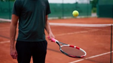 Genç tenis oyuncusu antrenörü tenis kortunda raketle topa vuruyor ve spor yaşam tarzı yarışmasına hazırlanıyor.