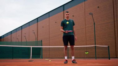 Genç tenisçi koç tenis kortunda raketle topa vuruyor ve spor yaşam tarzı yarışmasına hazırlanıyor.