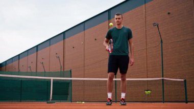 Genç tenisçi koç tenis kortunda raketle topa vuruyor ve spor yaşam tarzı yarışmasına hazırlanıyor.