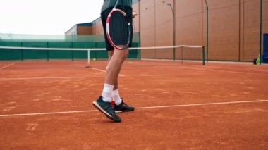 Açık hava tenis kortunun genç profesyonel oyuncu koçu raket tenis topuyla vuruşlar yapıyor.