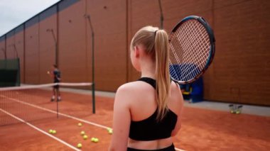 Sahada raketle tenis oynamadan önce geriye bakan kızlar hobi olarak maç antrenmanı sporu sporu yapıyor.