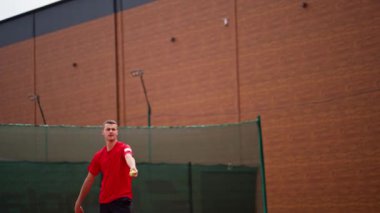 Açık hava tenis kortunun genç profesyonel oyuncu koçu raket tenis topuyla vuruşlar yapıyor.