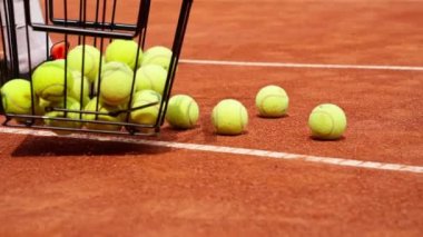 Spor malzemeleri yarışması eğitiminde profesyonel bir sepetin içinde tenis topları topluyor.