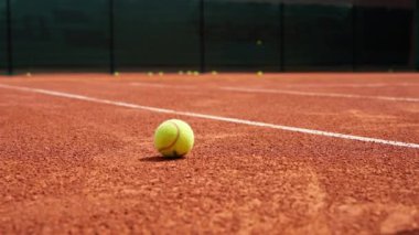 Tenisçi ya da koç maç spor ekipmanları kapandıktan sonra kortta tüple tenis topları topluyor.