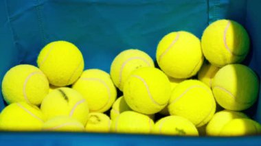 Spor müsabakası sahasında bir sepette duran birçok tenis topunun yakın çekimi.