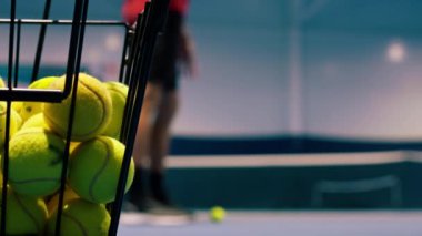 Spor müsabakası sahasında bir sepette duran birçok tenis topunun yakın çekimi.