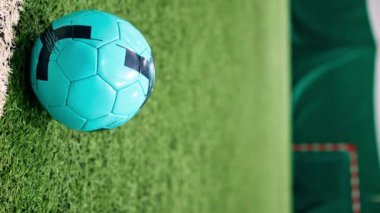 Bir futbolcunun penaltı ya da gol için topa tekme attığı ya da futbol maçında yeşil sentetik çimlere top attığı dikey video görüntüsü.